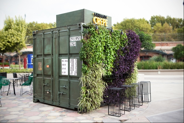 Un contenedor reciclado con un jardín vertical en una de sus paredes.