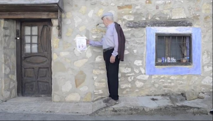 Un abuelo toma el cartel dibujado. "Se buscan niños" para poblar la escuela. Captura de video