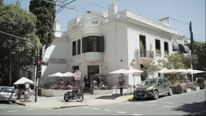 La panera rosa tiene un patio delantero y mesas en la vereda.