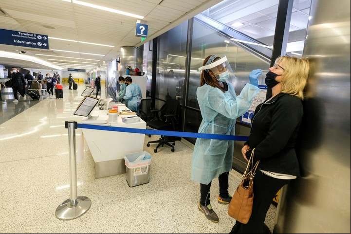 Una enfermera hispando a una pasajera en un aeropuerto. Foto Shutterstock.