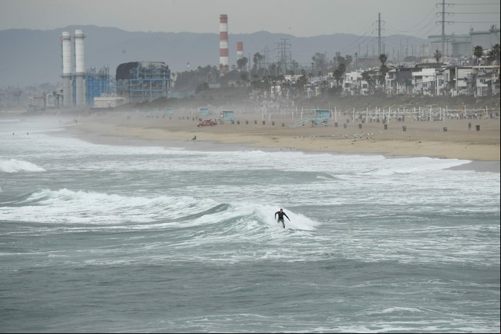 A surfer catches a wave at Manhattan Beach in El Segundo, California, on January 15, 2022. - The US National Weather Service issued tsunami advisories for the entire west coast of the United States following a massive volcanic eruption across the Pacific Ocean in Tonga. (Photo by Patrick T. FALLON / AFP)