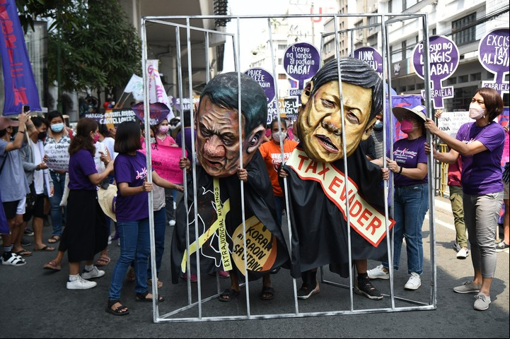 Mujeres activistas sostienen una celda de prisión improvisada con colegas que llevan máscaras que representan al presidente Rodrigo Duterte (L) y Bongbong Marcos (R), para celebrar el Día Internacional de la Mujer en Manila el 8 de marzo de 2022.
Foto de Ted ALJIBE / AFP)