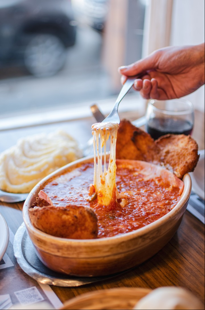 La milanesa viene con abundante queso y salsa de tomate.