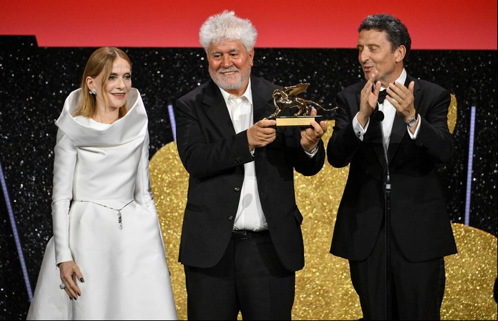 La presidenta del jurado Isabelle Huppert y el presidente de la Biennale, Pietrangelo Buttafuoco, junto a Pedro Almodóvar con su León de Oro. Foto: EFE