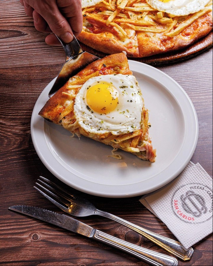 El invento de poner papas Gramajo es poner sobre la masa: salsa de tomate, mozzarella, jamón, papas fritas, arvejas y huevo frito. Foto: Instagram @sancarlos.pizzeria.