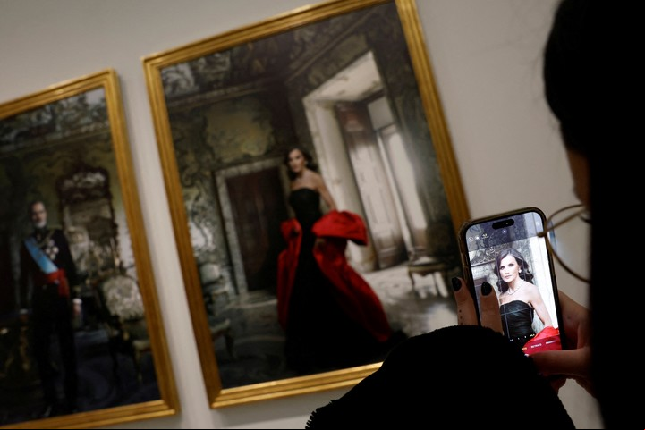 Una mujer toma una foto de una etiqueta junto a los retratos de los Reyes de España Felipe y Letizia realizados por la fotógrafa estadounidense Annie Leibovitz. REUTERS/Susana Vera