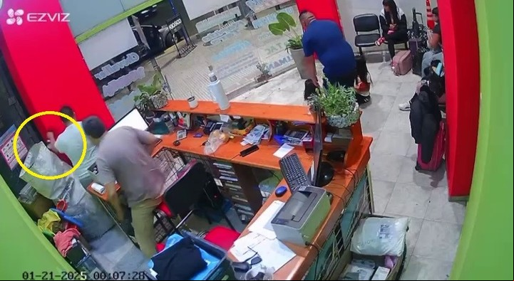Antes de que entren los ladrones, un empleado logra esconder su campera con algunos objetos atrás de una columna.