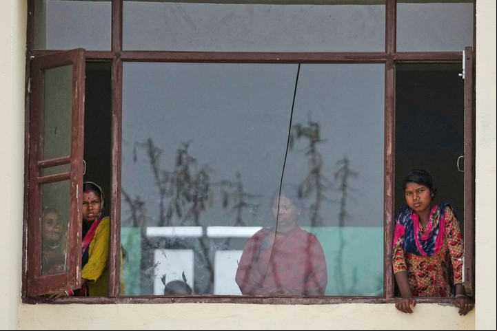 Aldeanos que viven a lo largo de la frontera entre India y Pakistán miran desde la ventana de un colegio donde se han refugiado tras los bombardeos de artillería desde Pakistán, en las afueras de Jammu, India, viernes 9 de mayo de 2025.(AP Photo/Channi Anand)