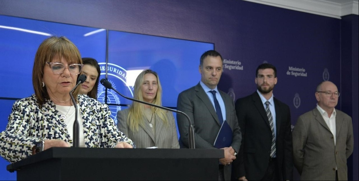 Patricia Bullrich en un anuncio para impedir que los barras viajen a EE.UU. Detrás, Adorni y Karina Milei.Foto: Prensa